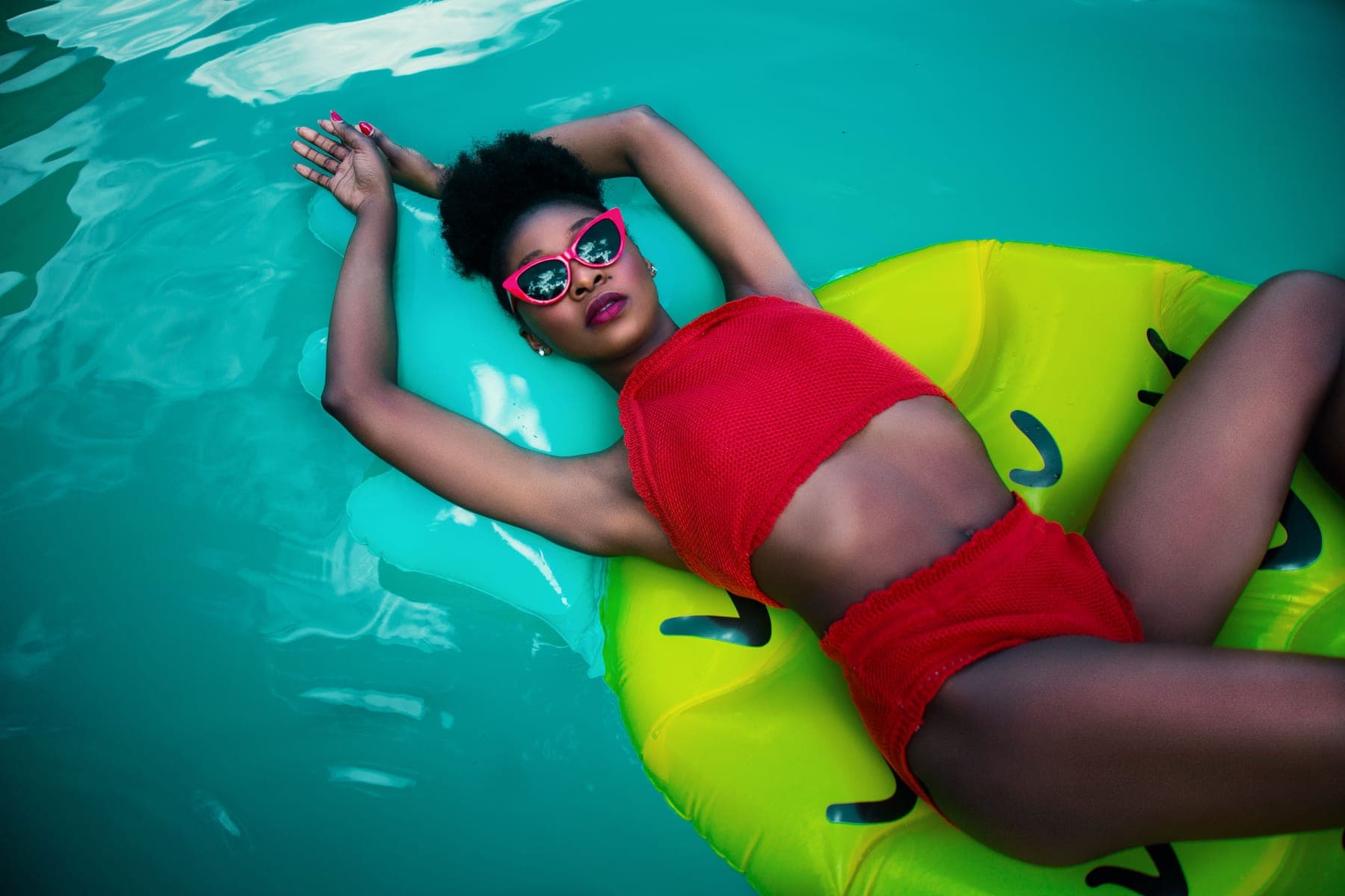 A client in a red swimsuit and pink sunglasses relaxing on a pool float